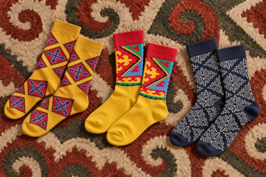 Drei Paar Nomad Socks mit kirgisischen Mustern auf einem Schyrdak-Filzteppich